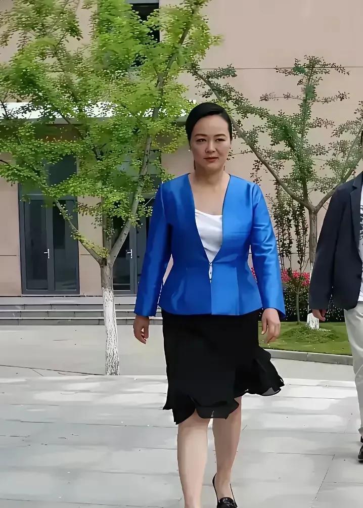 孙晓梅穿着蓝色的上衣，黑色的裙子，头发高高盘起，这气质杠杠滴！孙晓梅独特的魅力