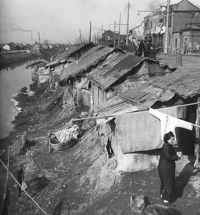 1947年，上海，贫民窟。上海的龙须沟臭水浜——肇嘉浜，远处的烟囱可能就是大中华