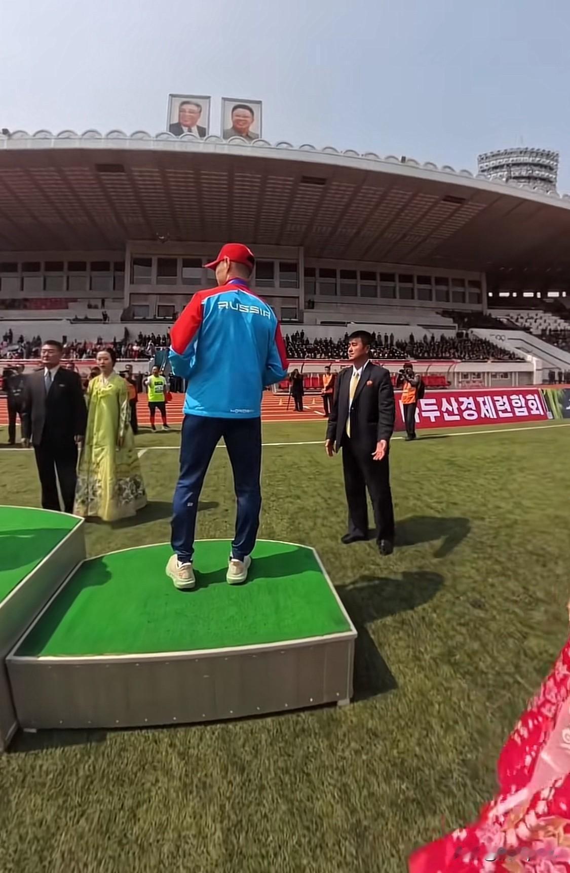 外国运动员用隐藏摄像机拍下朝鲜体育场景象。朝鲜举办国际比赛，草坪是人造草皮。这令