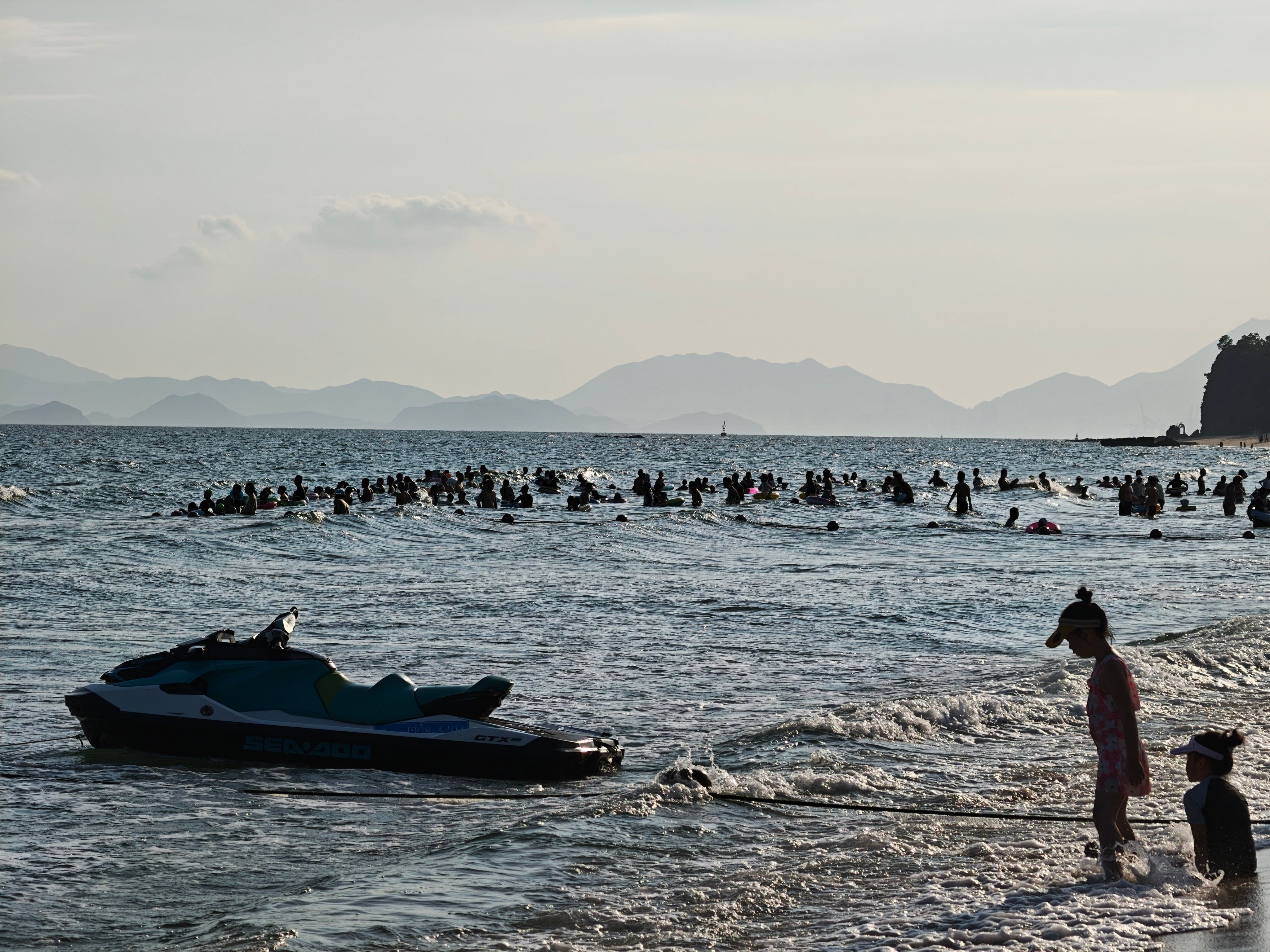 暑假的海边沙滩人多海里垃圾多​​​
