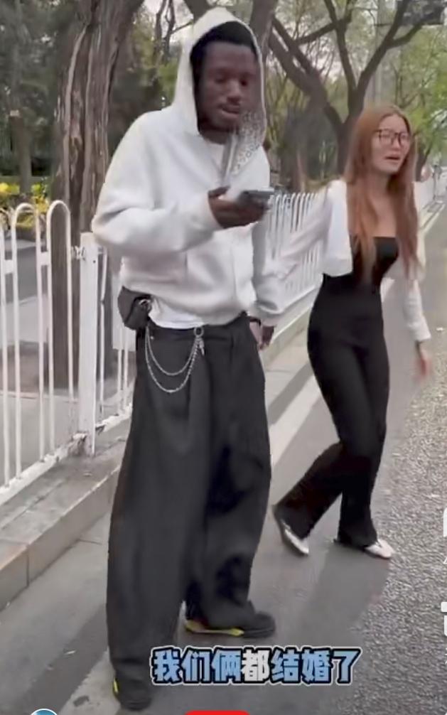 一女子带着非洲籍老公逛街。许多路人追拍。女子骄傲的说，我们都结婚了。路人不
