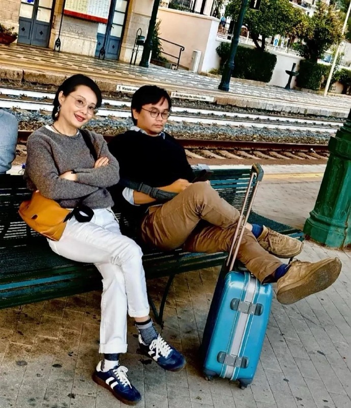 著名演员袁立，和小12岁的老公，在国外的小火车站留影。袁立留着一头短发，一身休