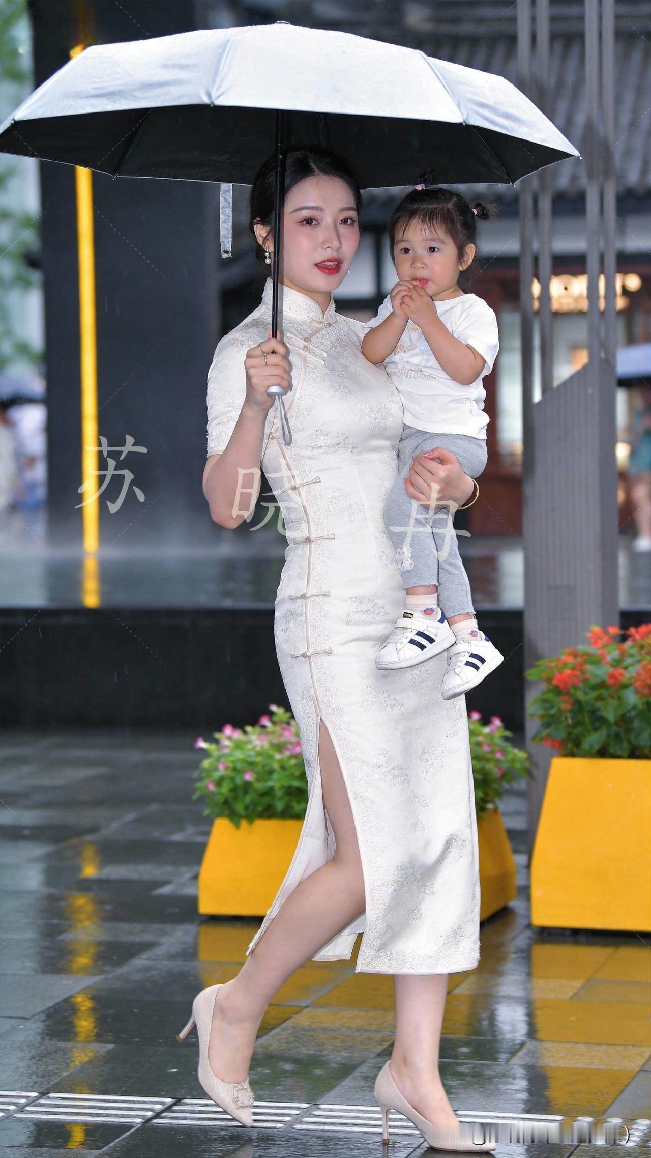 一场细雨浸润了街头巷陌，母亲携稚子漫步雨中，偶遇淋雨的小猫便暖心呵护，举手投足皆