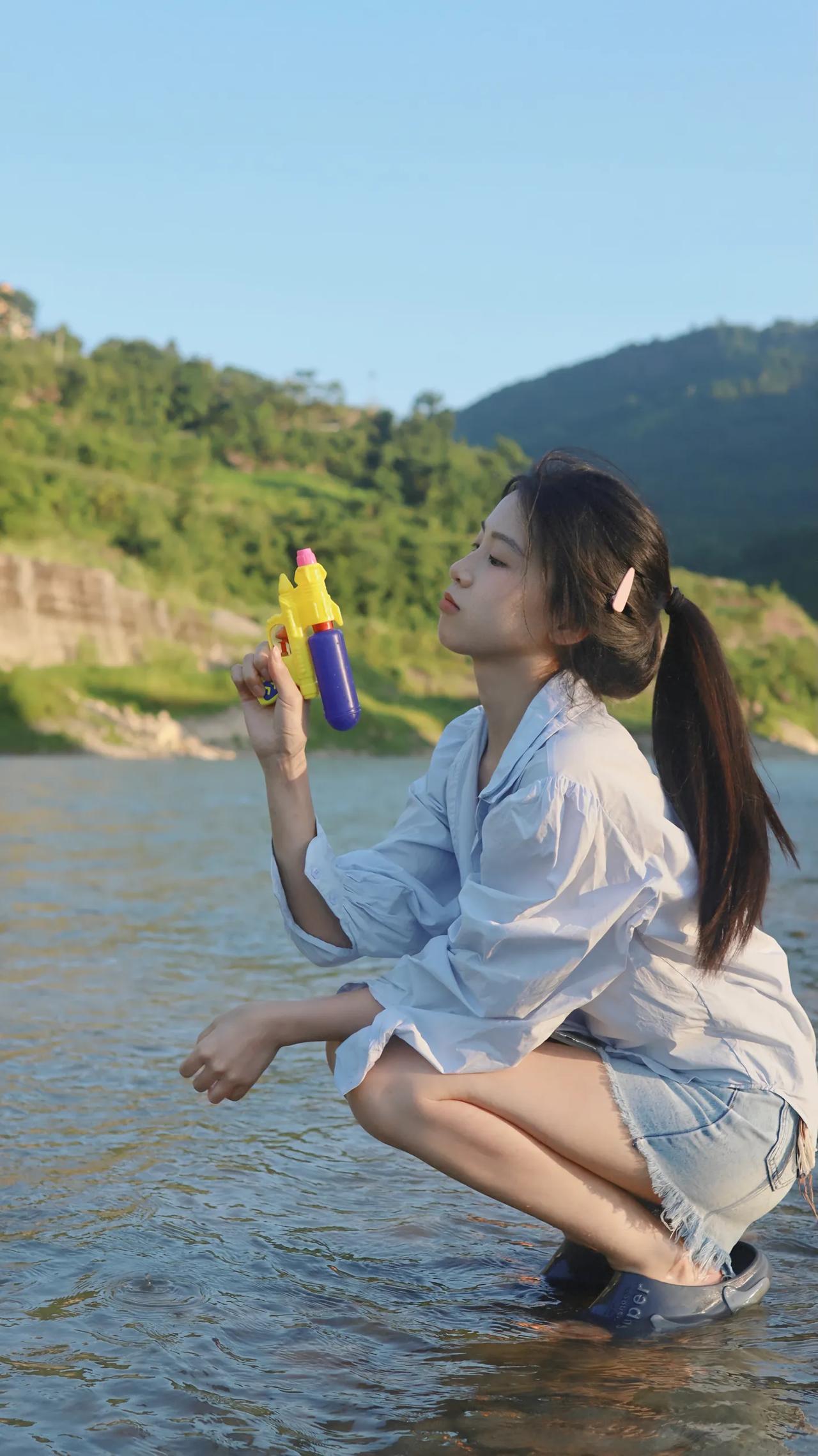 水边嬉戏人，手持水枪乐。