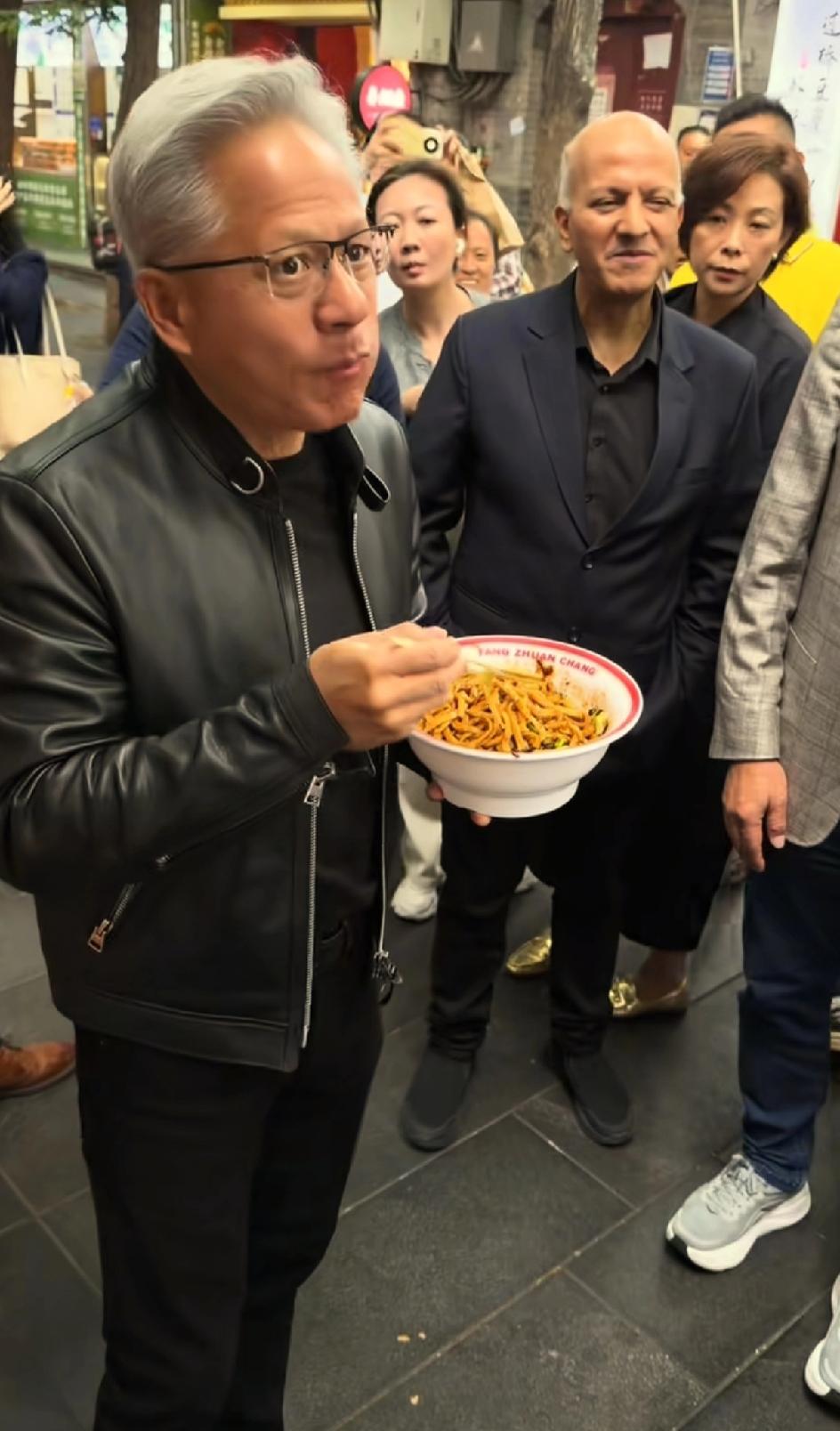 黄仁勋逛北京城和小朋友合影，还送给小朋友一盒点心。他吃了炸酱面，还吃了鱿鱼串，吃