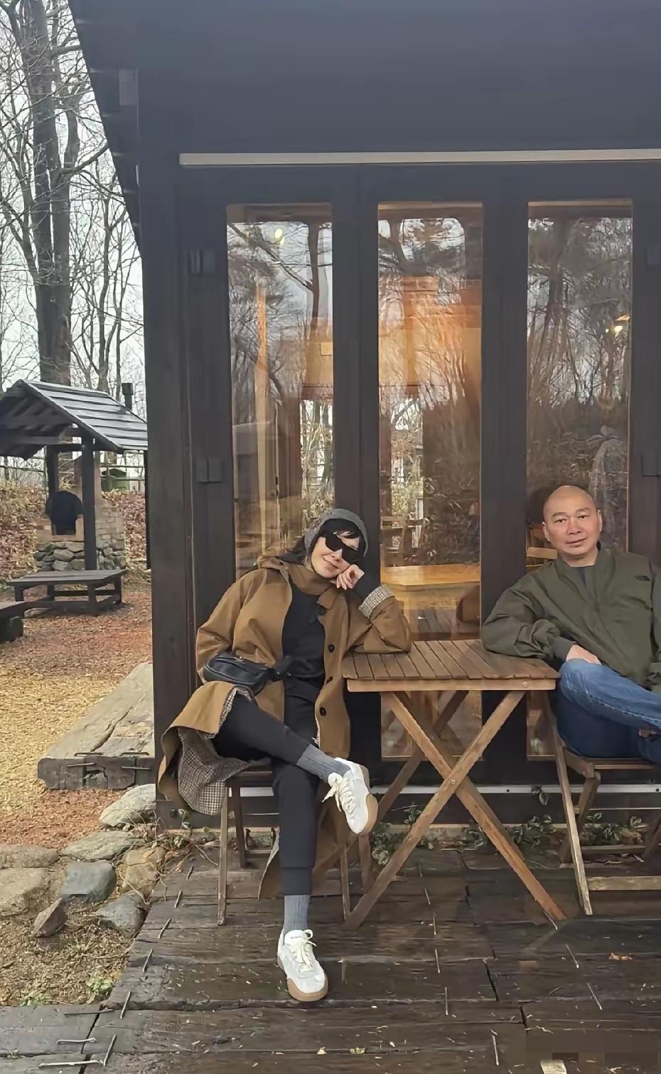 刘嘉玲与家人国外度假，与母亲牵手而坐，画面温馨。她头戴毛线帽，身穿咖色外套，神态