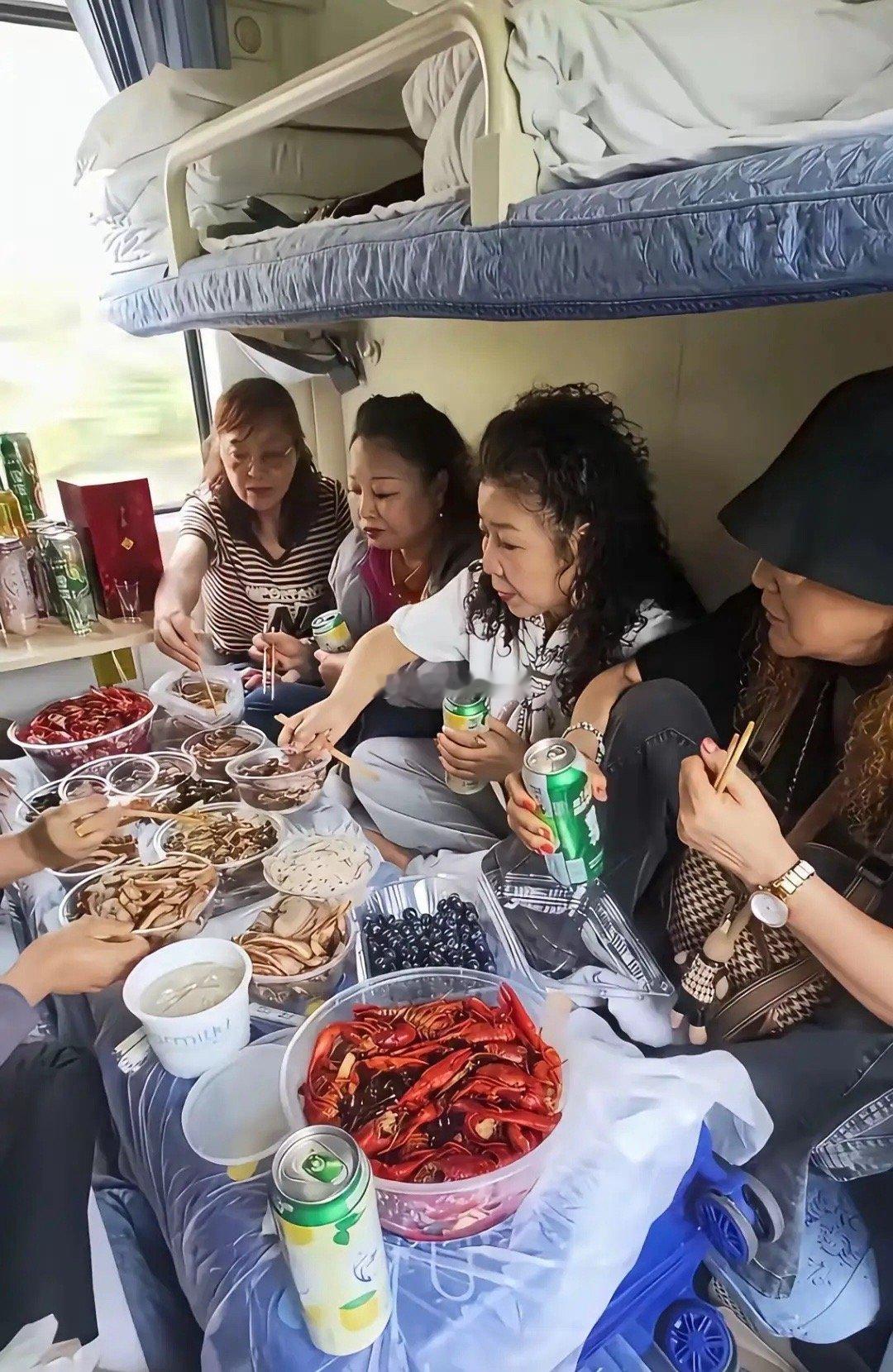 一位网友在火车上拍到的，一群中年大妈，带了很多的美食，在火车上面聚在一起，还有啤