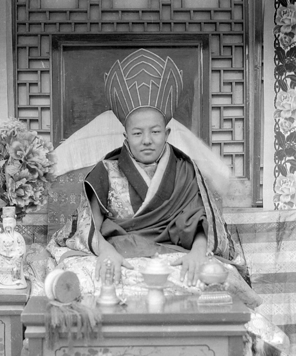 这是五世嘉木样大师照片里他坐在宝座上，身着传统僧袍，头戴高帽，面前摆着宗教用品