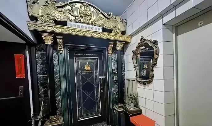 一梯两户，隔壁邻居把自家入户门装得格外隆重。黑金配色搭配繁复鎏金雕花，罗马柱配