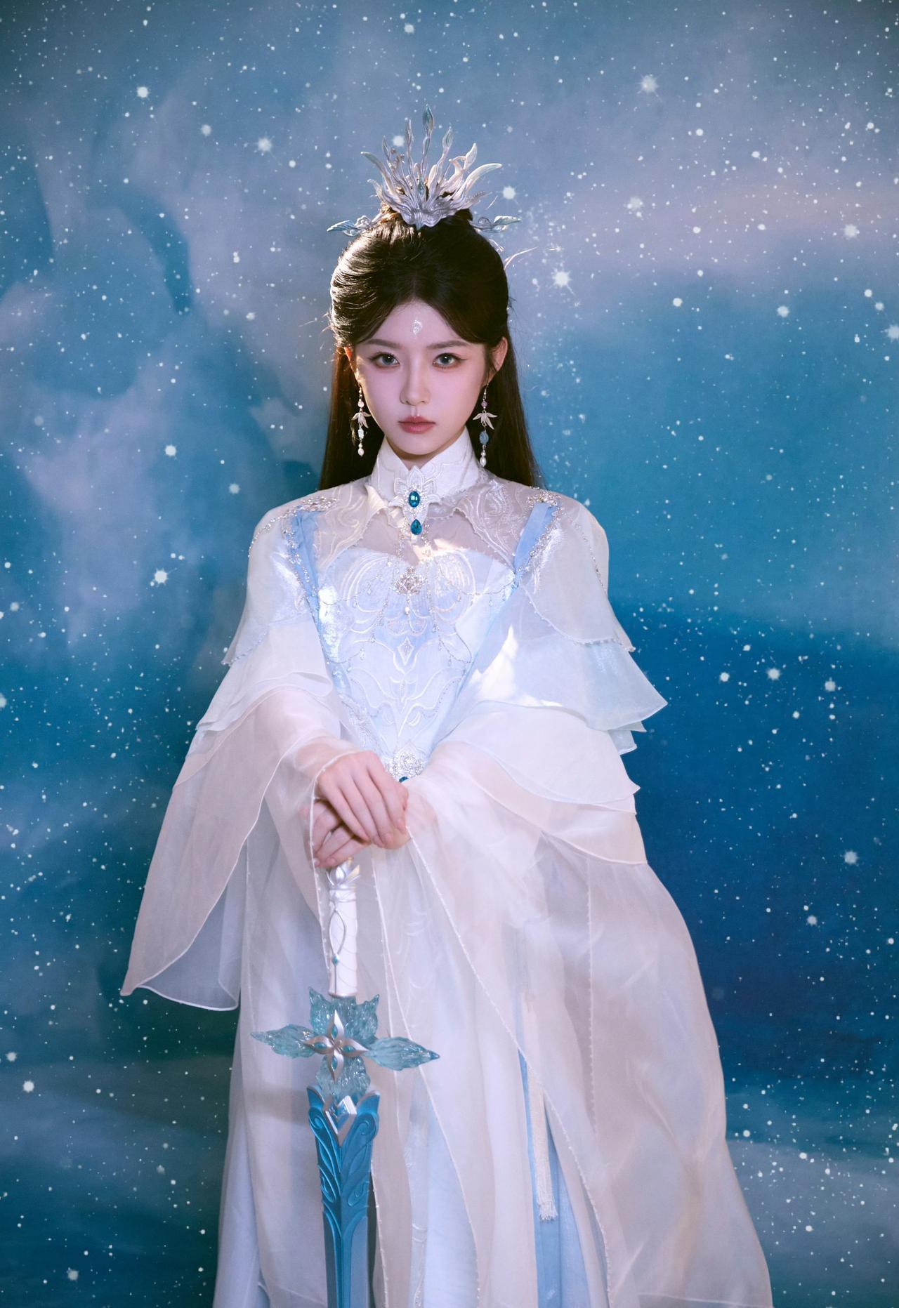 何蓝逗身着带有冰雪元素的古风服饰，手持一把装饰精致的蓝色宝剑，整体造型仙气十足，