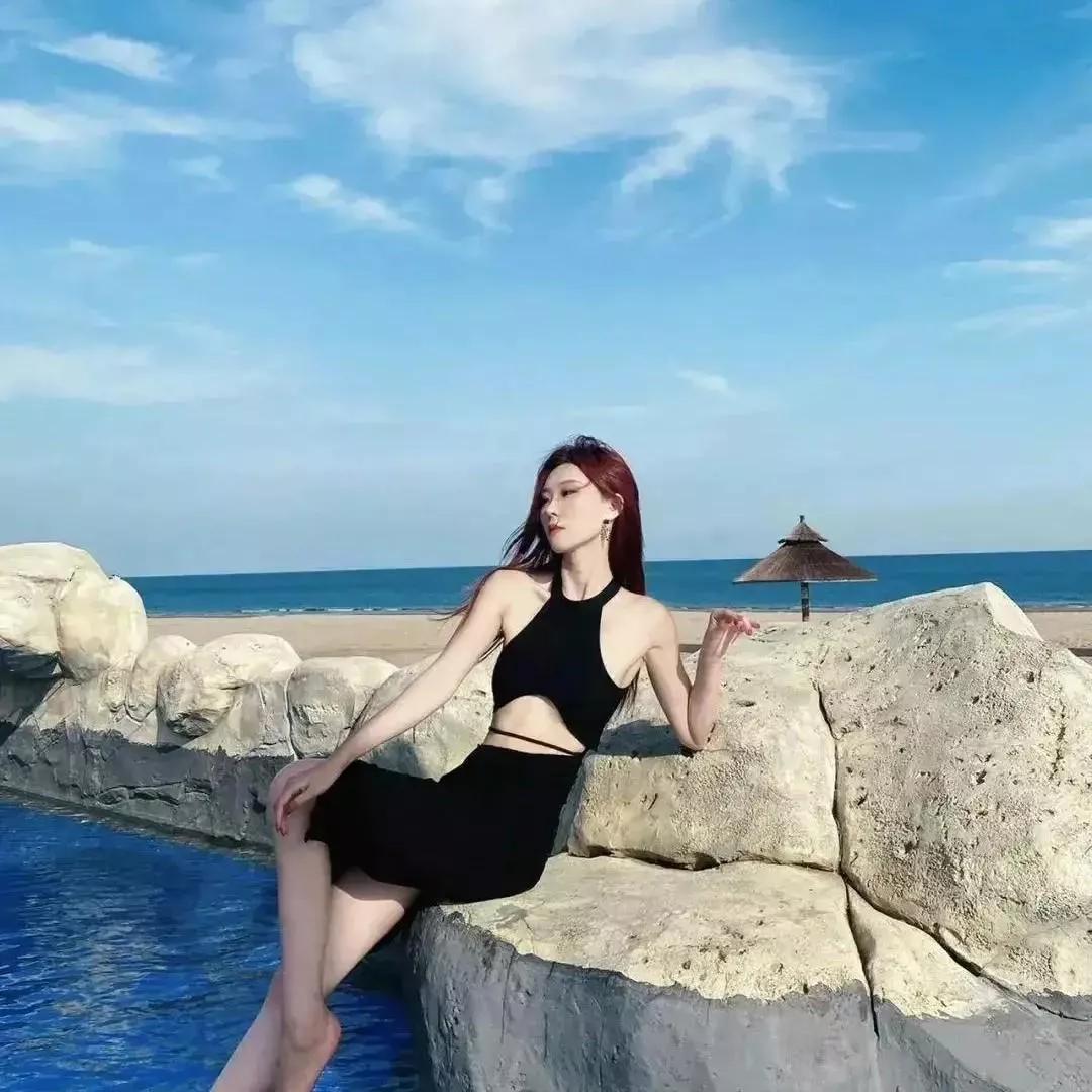 海边度假风，红发美人倚石而坐，阳光正好，心情舒畅。海边度假少女海边游玩美女美