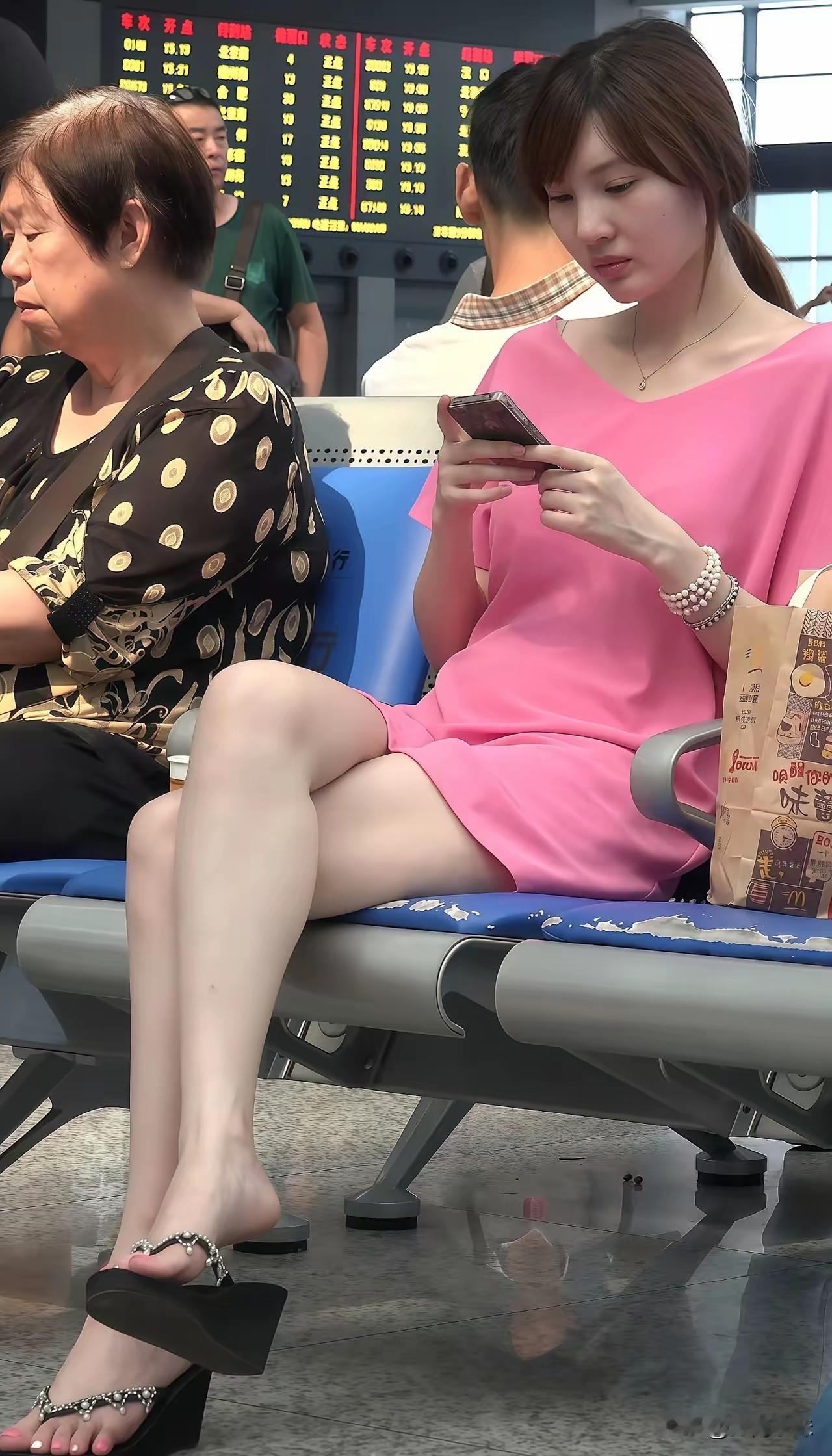 粉裙美眉低头玩手机，时尚又舒适。