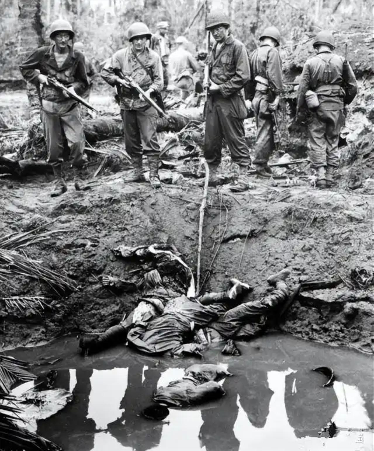 这张黑白老照片记录了第二次世界大战太平洋战场的残酷战斗场景。画面里几名美军