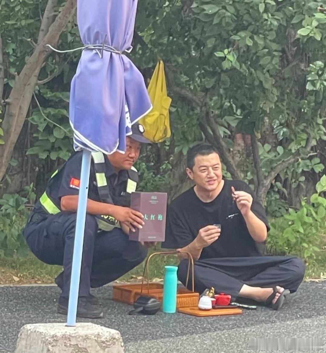 54岁李亚鹏现身北京798艺术园区，他穿着短袖T恤和拖鞋，看起来很悠闲。还坐在路