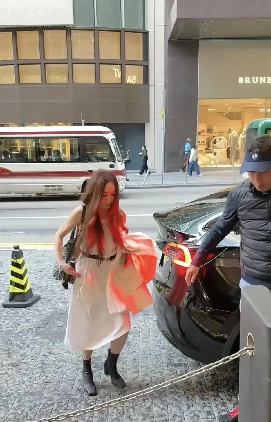 59岁温碧霞穿露肩白裙光腿现身置地广场，冷风里裙摆被吹起她只轻压一下。12℃的