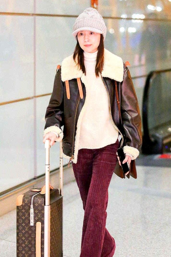 董洁这次机场的穿搭真让人眼前一亮。她一身羊羔毛外套，内搭基础款，配上枣红色长裤，