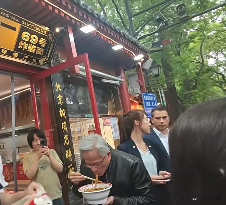 中午，英伟达老板黄仁勋端着一碗北京炸酱面，站在店门口大吃着，他边吃边对同行的人说