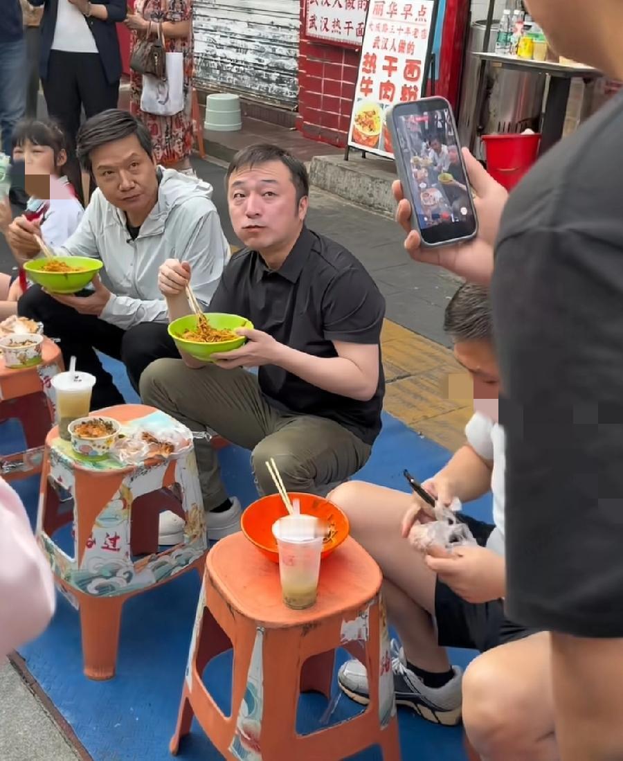 雷军蹲武汉街头吃热干面早饭，与助理徐洁云在店门口，一排塑料板凳饭桌，坐在一个矮板