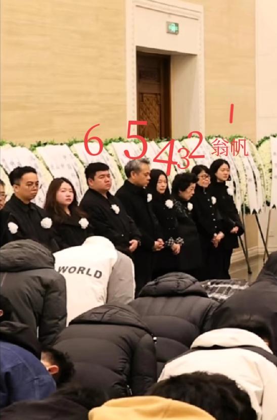 杨振宁告别会，在墙边站一排的家属区，翁帆站在第一位，第二位戴眼镜女士，疑似女儿杨