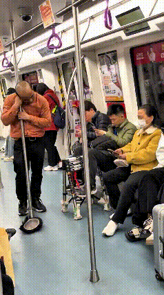 注意看！大哥在地铁上困得直点头，抱着扶手杆就睡着了，结果脑袋一低，假发“啪嗒”一