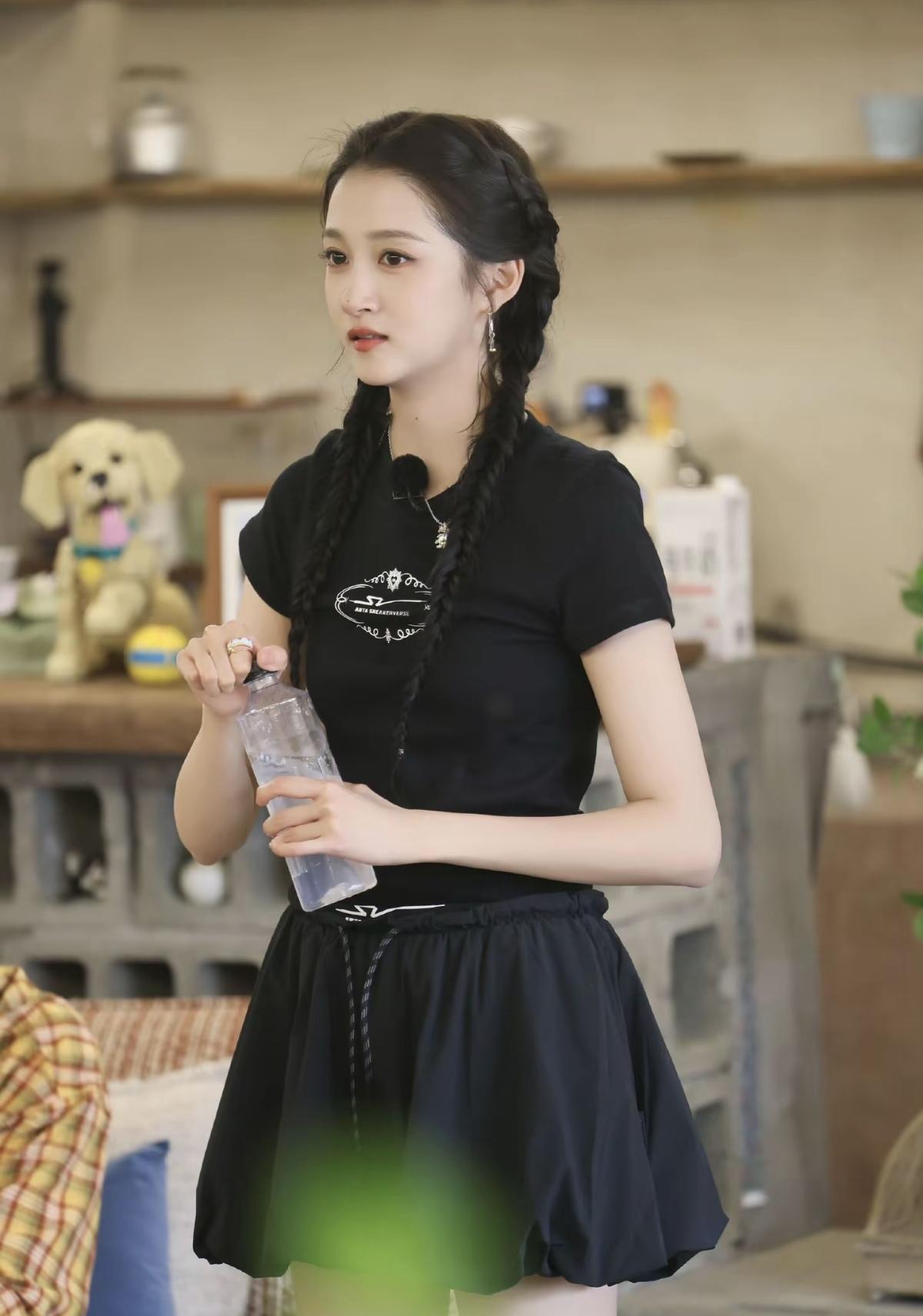 暖调温馨的小屋，两条麻花辫垂落肩头，褪去华丽礼服的关晓彤格外清爽。一身基础黑色休