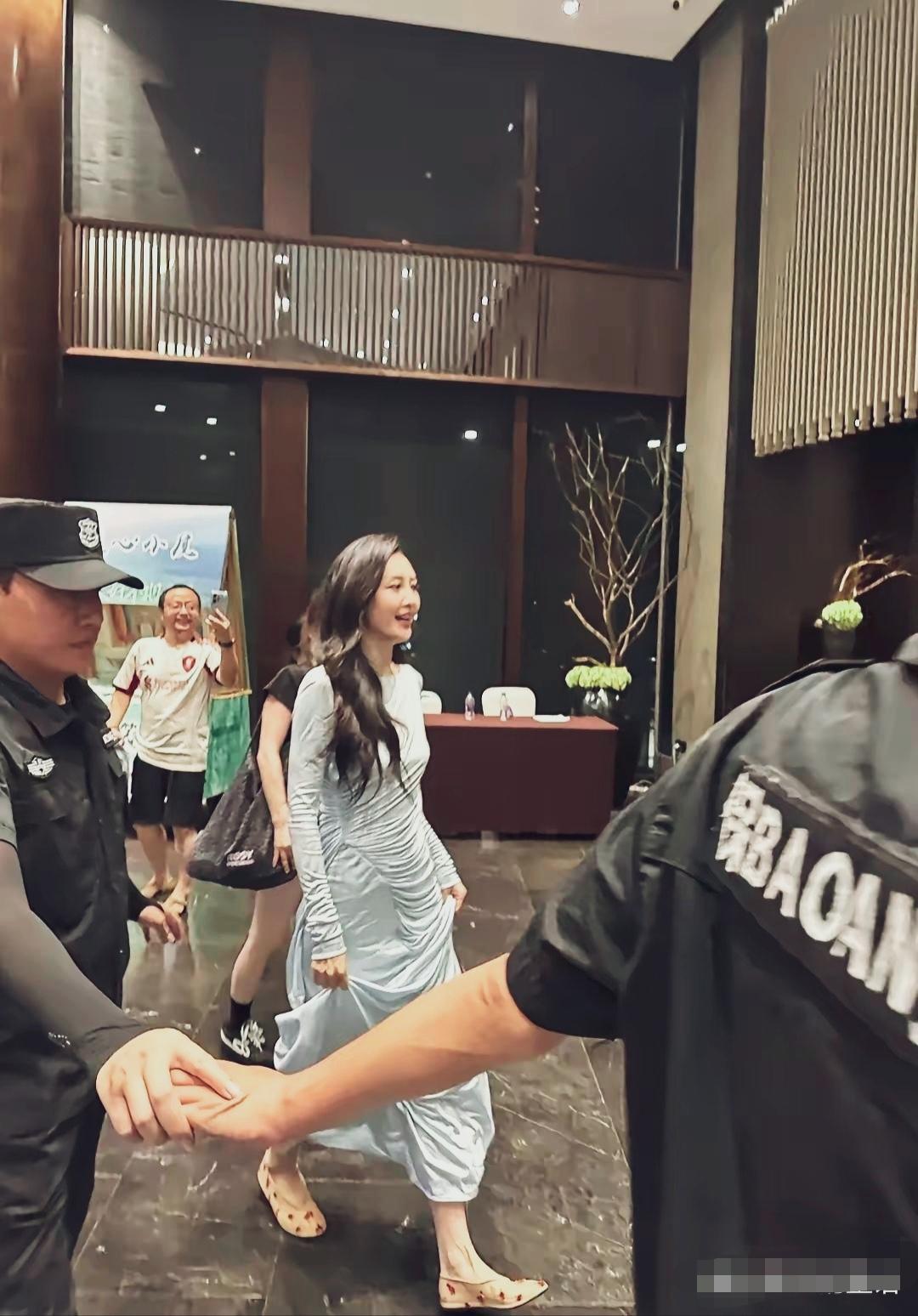 王鸥七夕晚会后台抓拍，一身冰蓝色褶皱长裙，平底鞋出行，眉眼柔和。安保人员牵手护