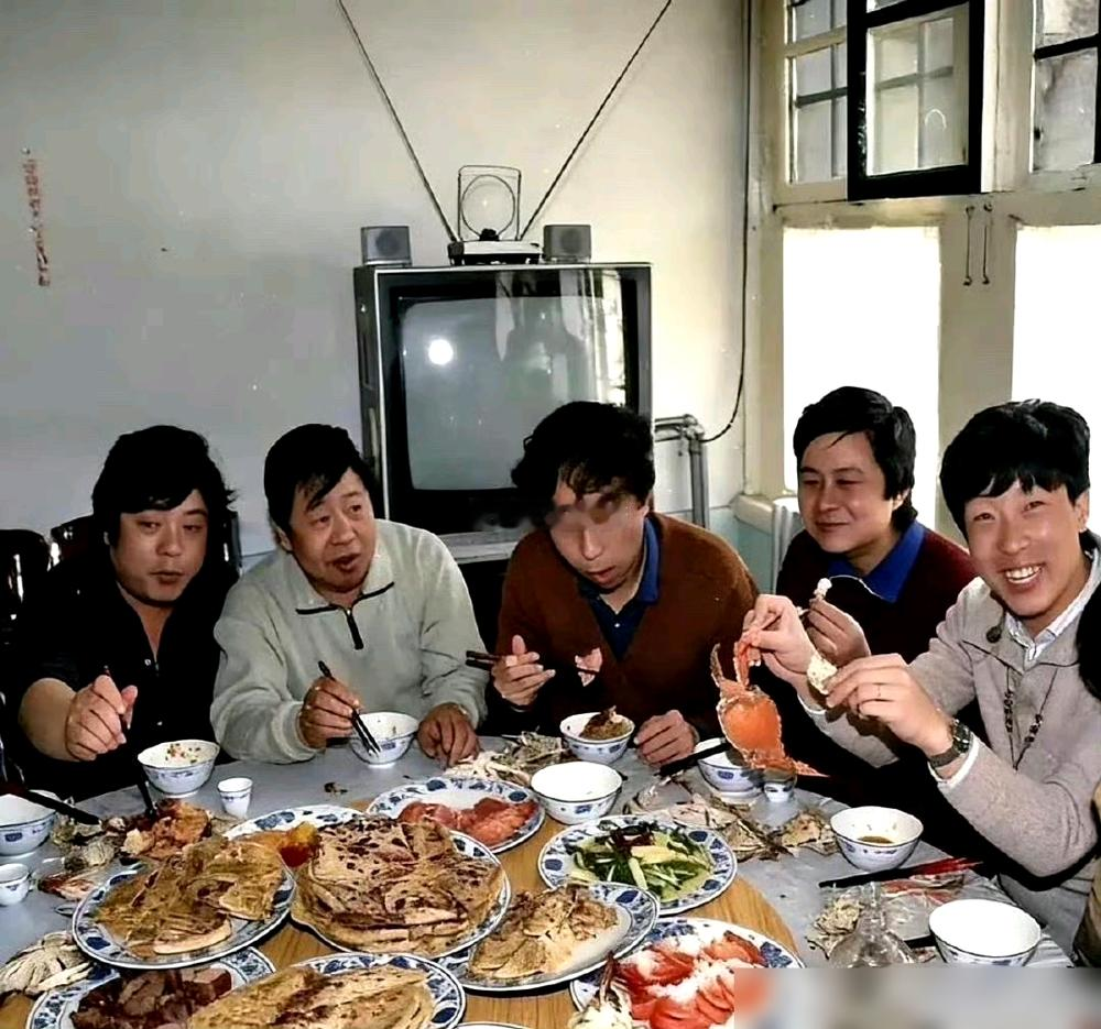一张老饭桌，仨人，一桌子硬菜，旁边还搁着一台带天线的大彩电。冯巩、姜昆、刘伟，当年曲艺圈最猛的一桌。