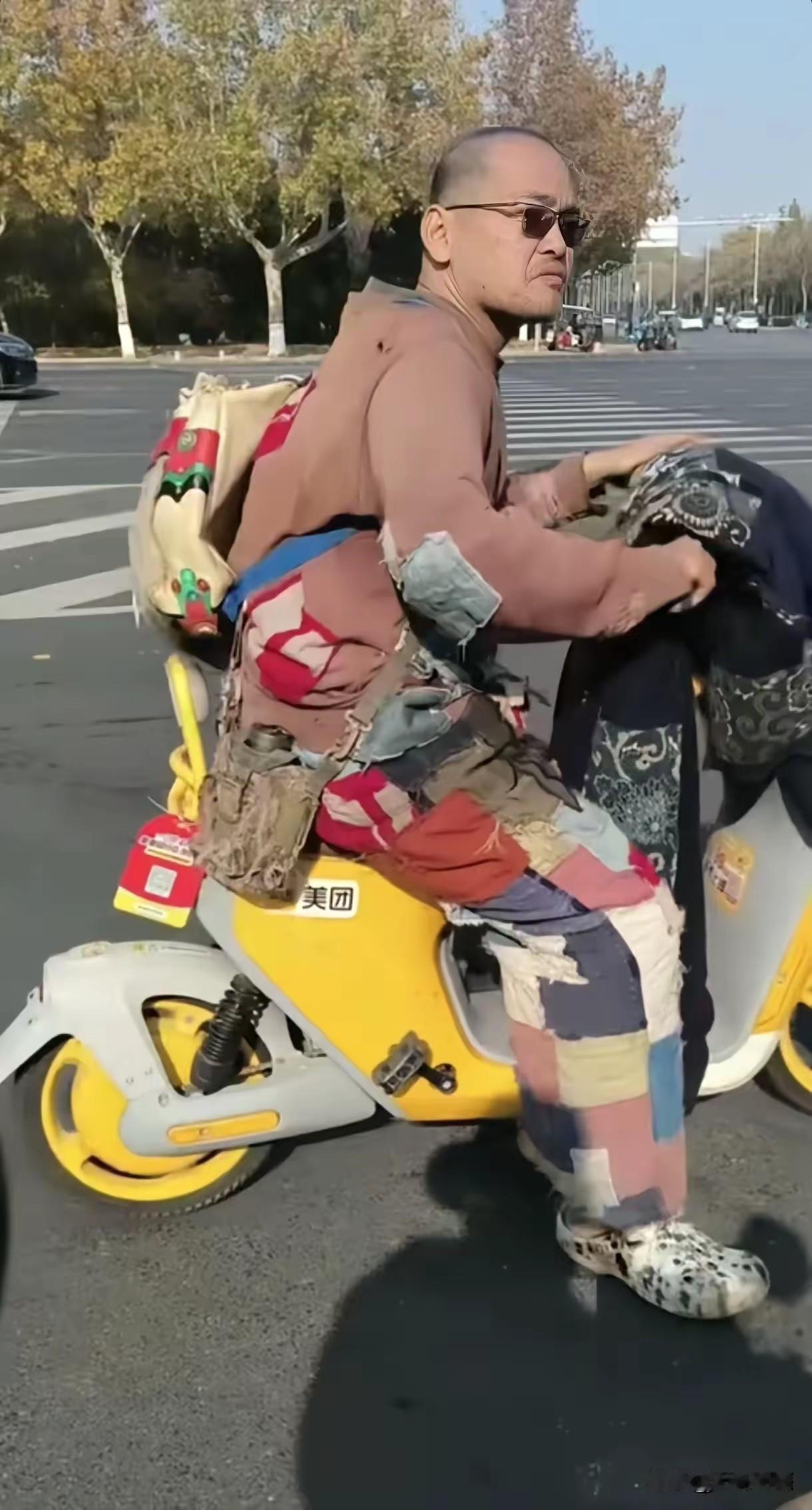 画面中这个骑摩托车的人，穿的衣服虽然全是补丁，不明白咋回事的，还以为是个要饭花子