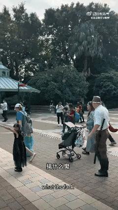 香港迪士尼乐园入口处，一个男人穿着鬼子军装、挎着东洋刀随着人流入园，旁边一个俄罗