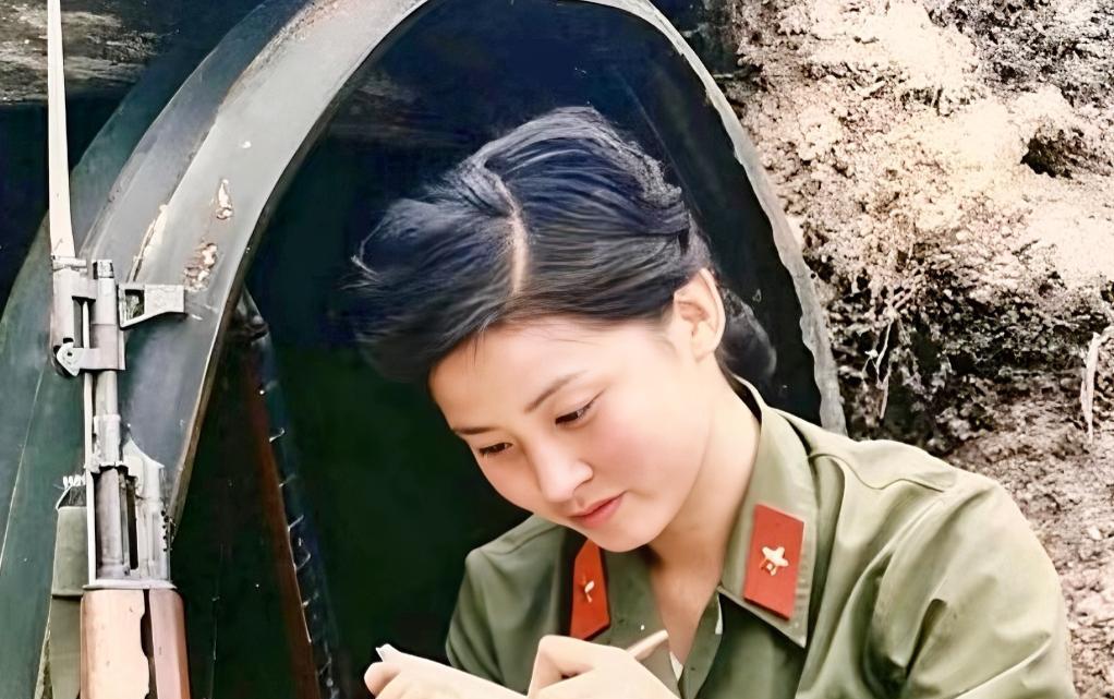 这张照片是对越自卫反击战中，一个年轻漂亮的女战士，正坐在猫耳洞外，全神贯注地给家