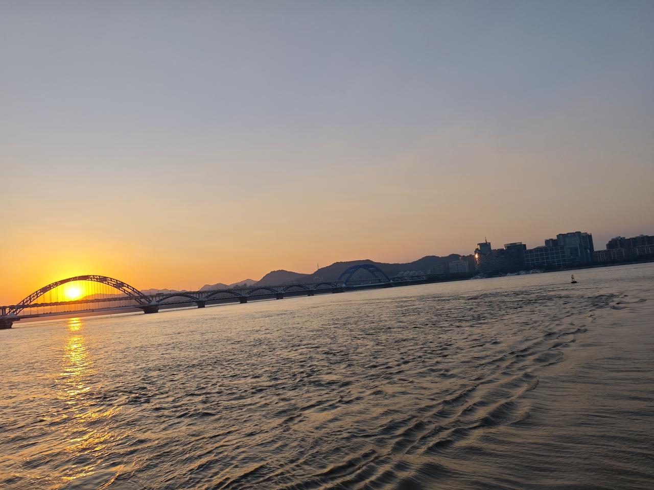 傍晚时分绝美的夕阳把钱塘江映射的绚丽多彩，壮观的钱塘江大潮和绿皮火车相互构成绝美