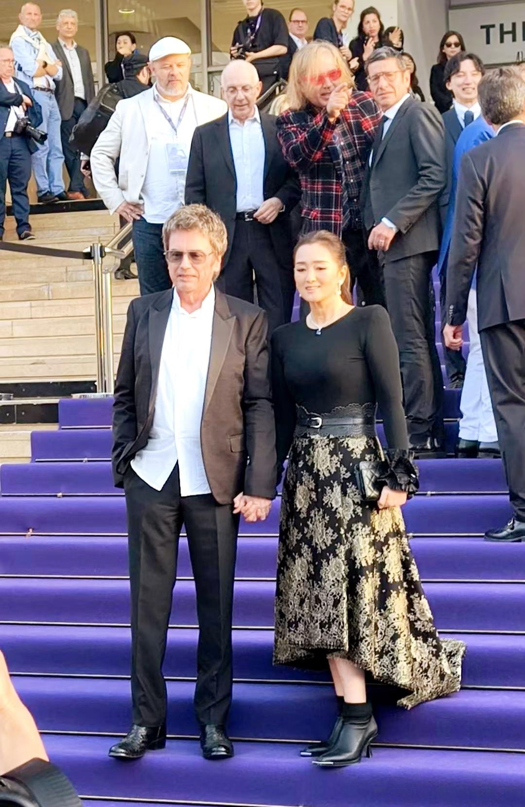 61岁巩俐和老公雅尔一起在法国参加电影节活动，夫妻俩牵着手到场，被好多记者围着拍