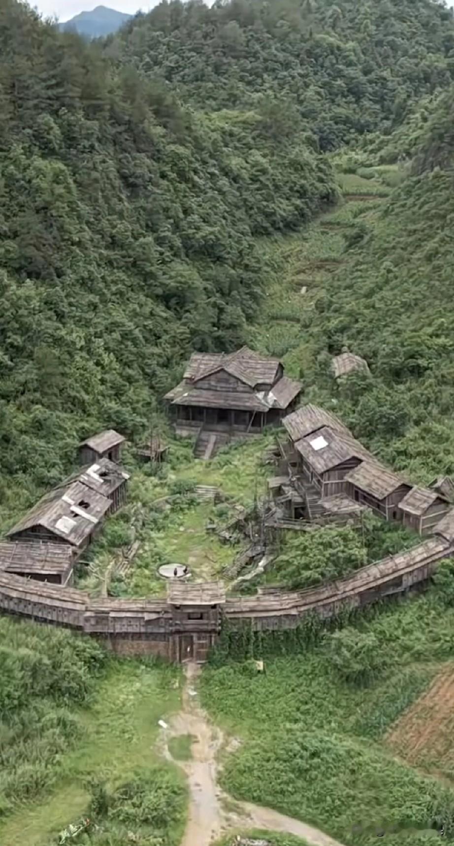 无人机拍摄到大山里面一群木制建筑群，建筑风格很特别，很像一个驻扎在山里的营房。