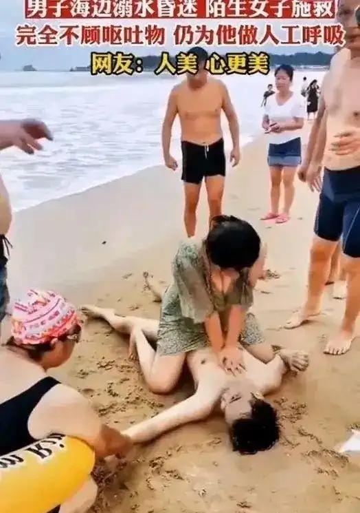 男子在海边溺水，心跳呼吸全没了。一个穿泳衣的姑娘冲上前，跪在沙滩上给人做心肺复苏