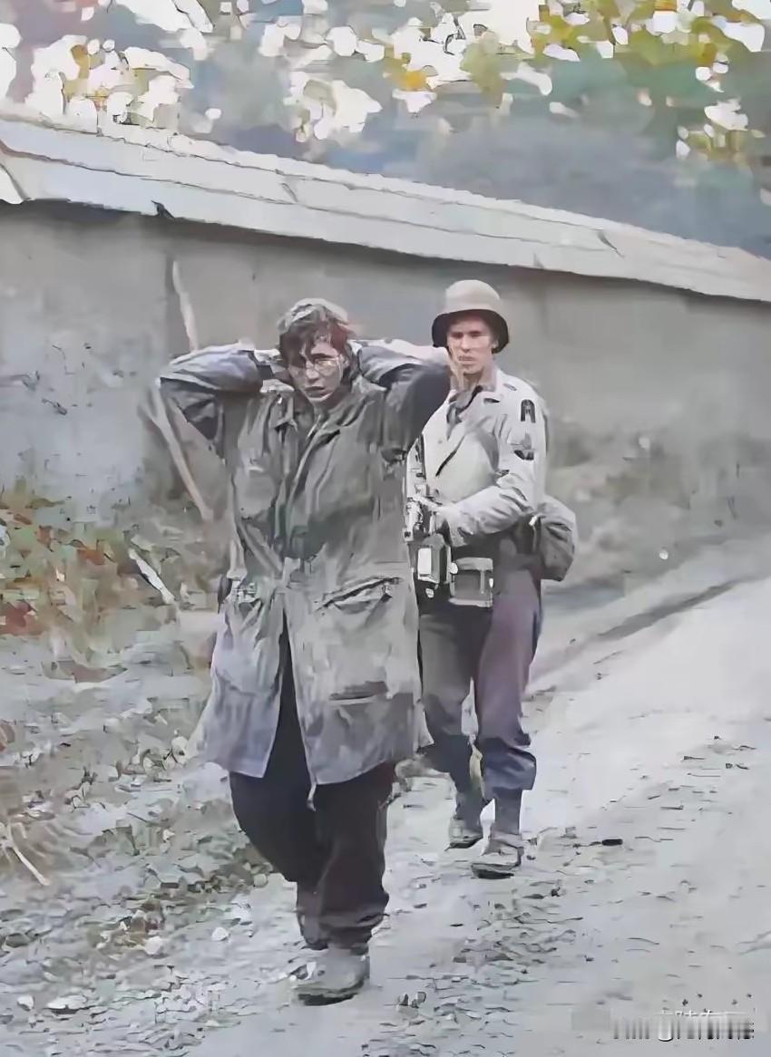 美国兵端着枪押着德国女战俘，女子双手抱着头，头发凌乱不堪，脸色也比较难看，身上穿