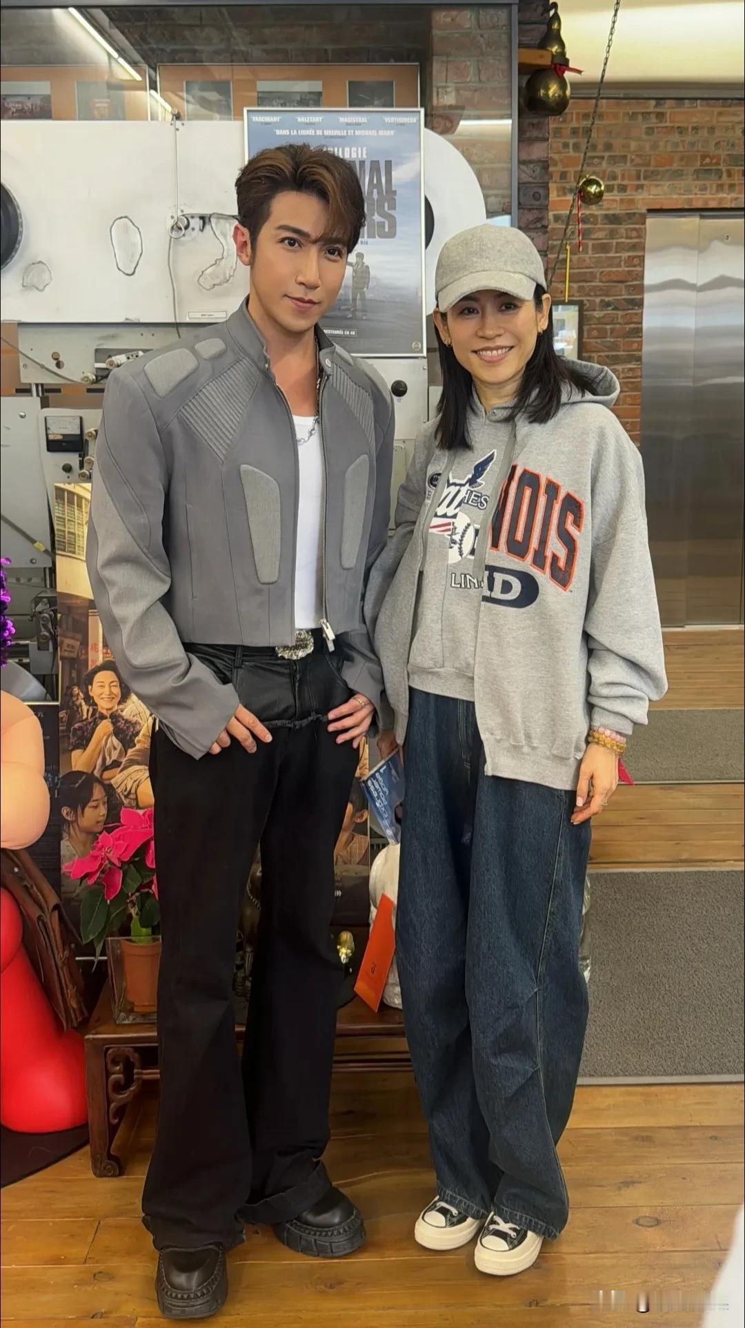 香港演员萱萱和朋友聚餐，穿着灰色连帽外套，戴着一顶灰色的棒球帽，蓝色弯刀裤，英姿