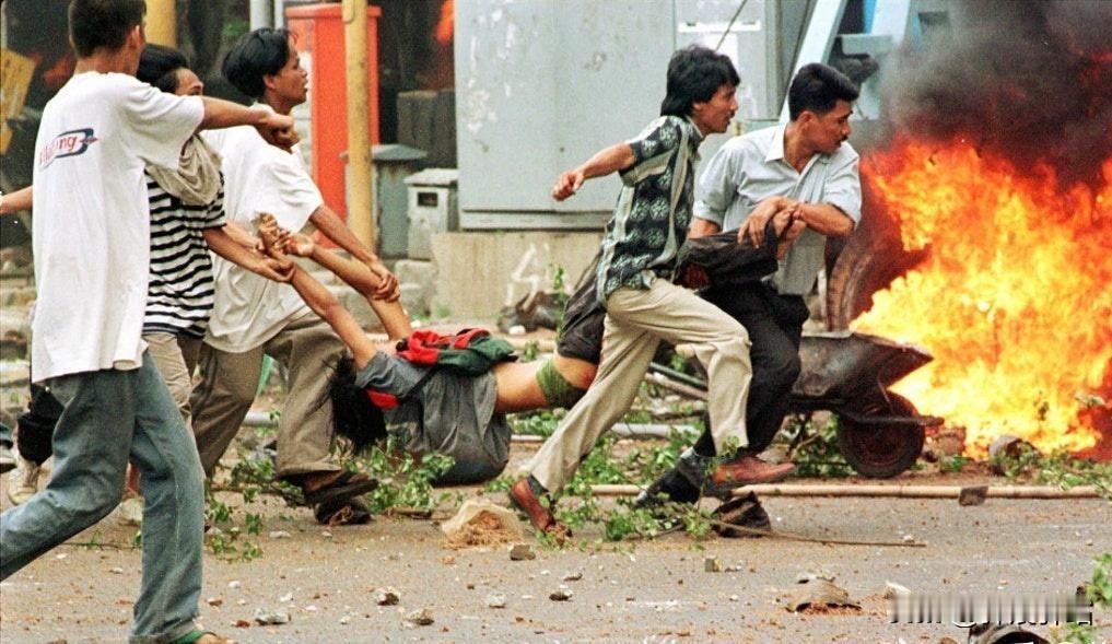 1998年，印尼雅加达“黑色五月”混乱现场的纪实照片。被众人抬着拖拽的是一名