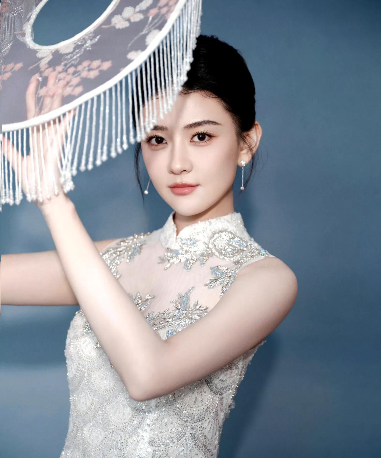 银缎裁身，绣纹藏韵，伞影流苏间，一回眸便晕染开东方的温婉绮丽。旧时光的诗意，在褶