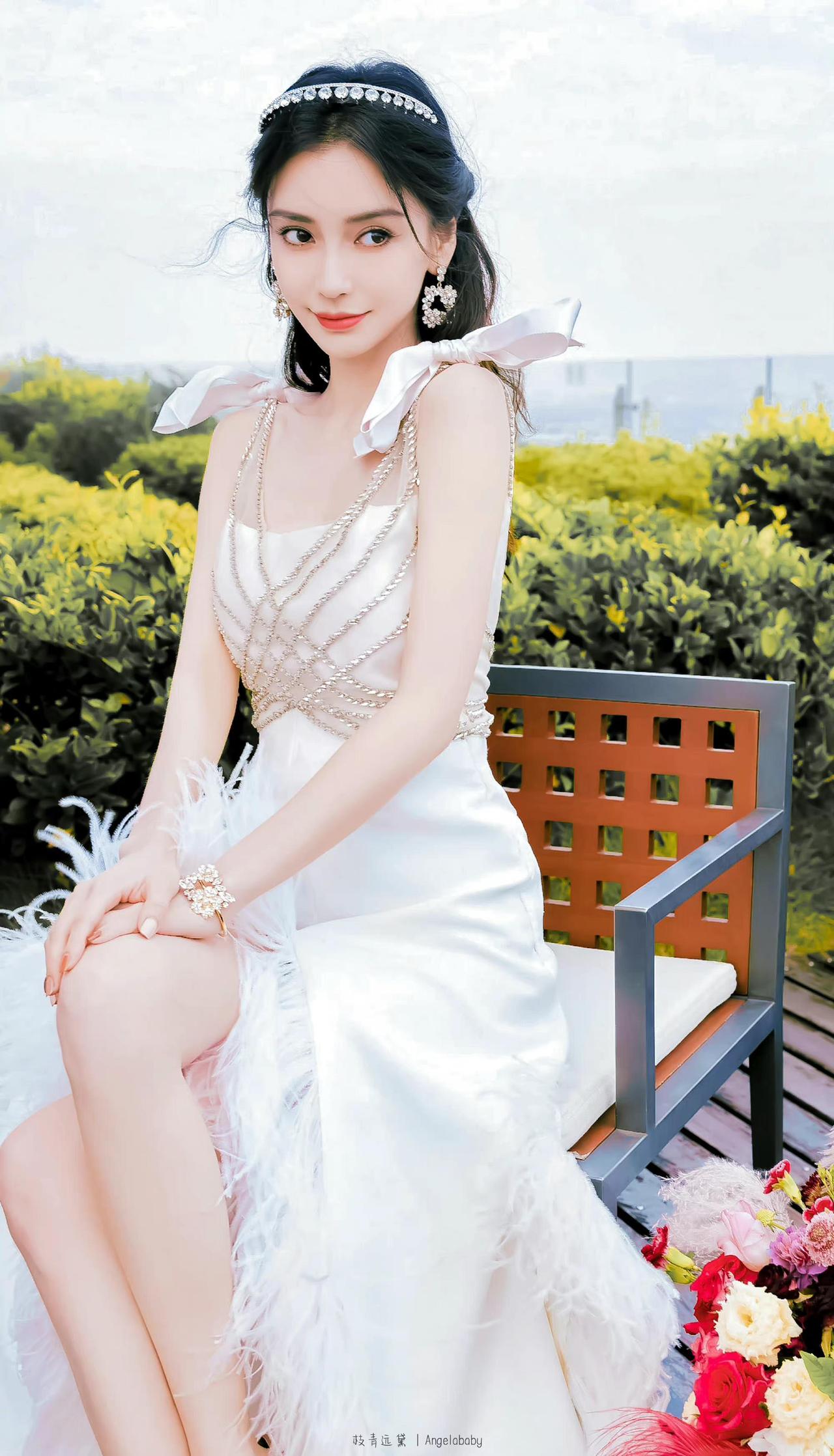杨颖穿白色晚礼服太让人惊艳了。她端坐在长椅上，五官精致，颜值出众，身后的绿植