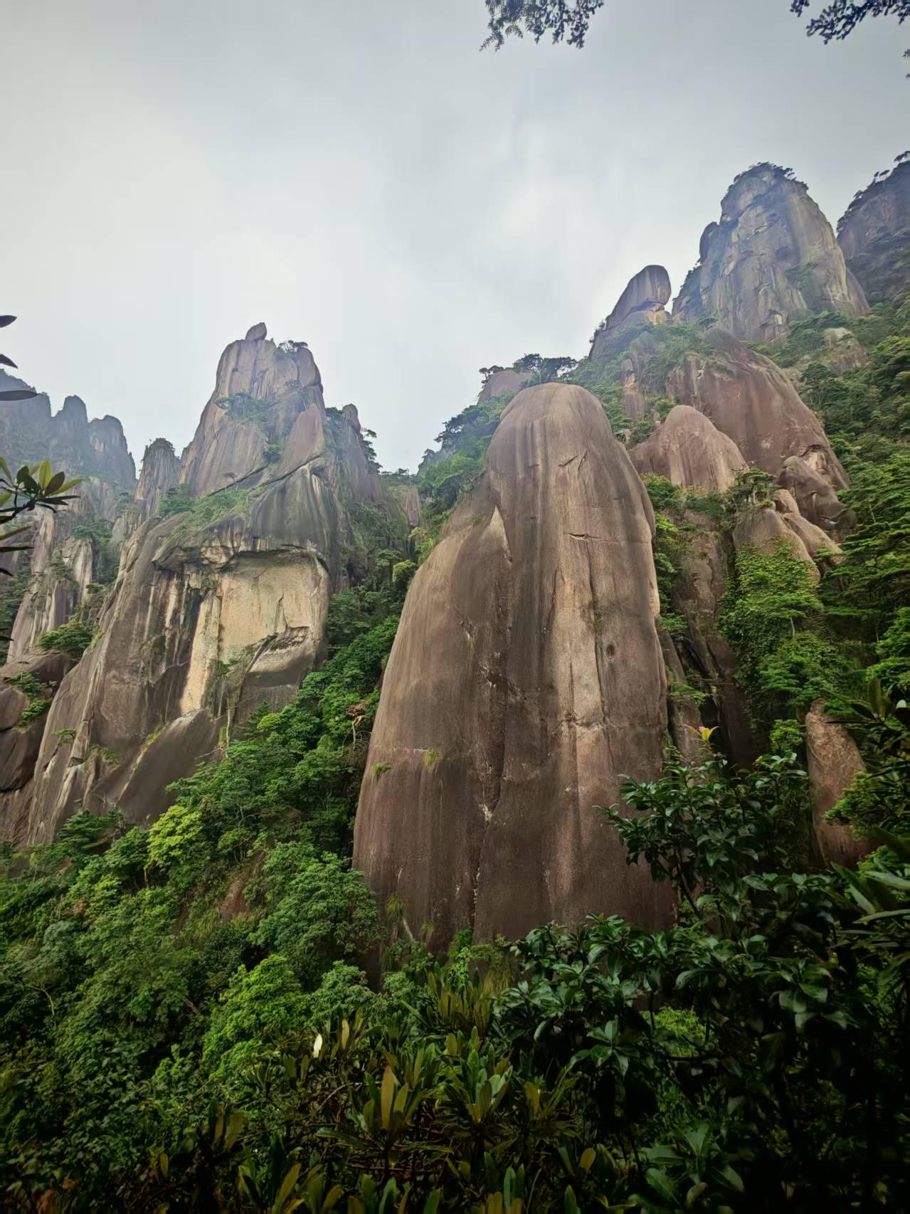 分享一张山景图片奇峰巨石巍然矗立，灰褐色岩体挺拔雄浑，岩壁纹理镌刻着岁月痕迹。漫