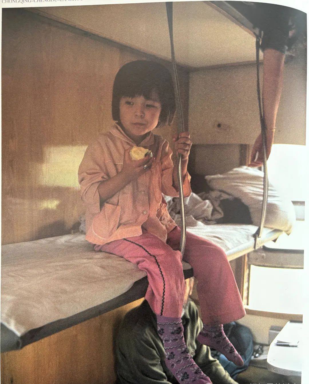 80年代，吃苹果的小女孩乘卧铺旅行，穿着整洁，家条件优渥。