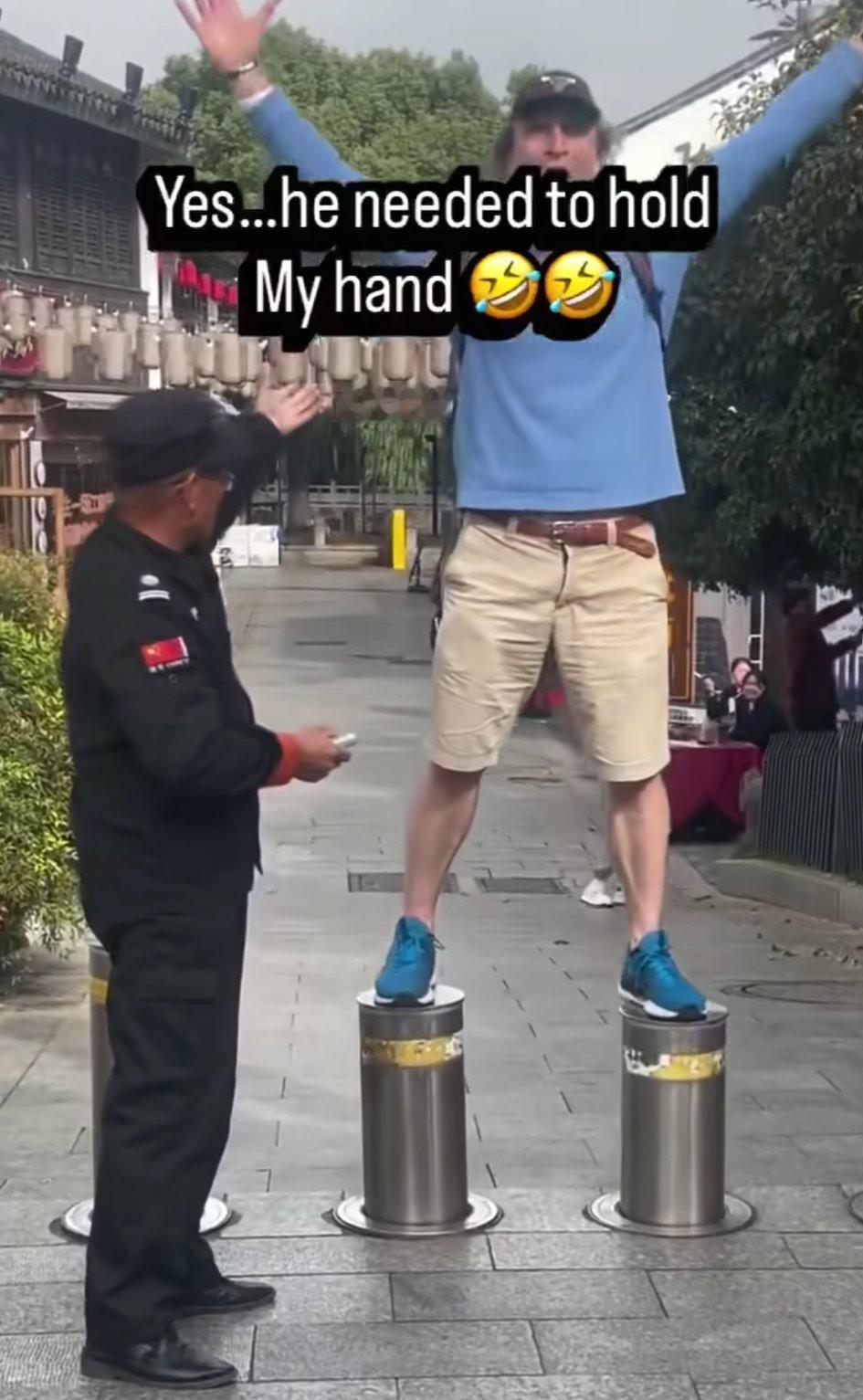 某地景区，保安让外国人站在升降桩上玩，生怕他摔下来，还非常贴心的用手扶着他……