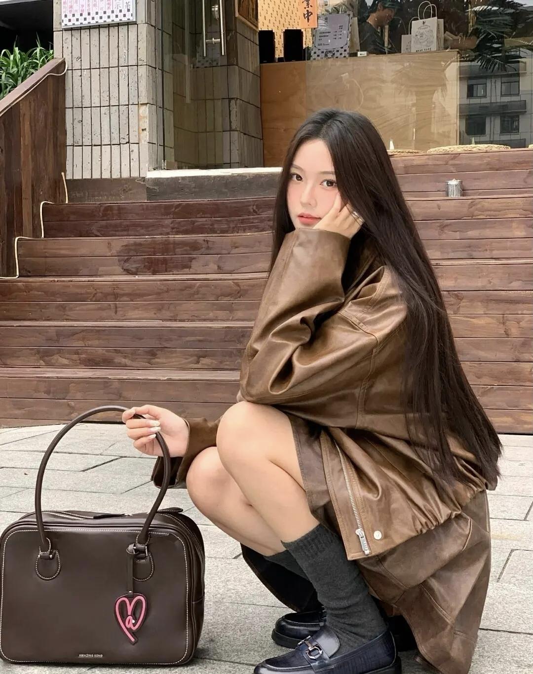 复古棕皮衣裹着街头的随性，老巷的海报与金属肌理撞出港风氛围感，抬手间都是不被定义