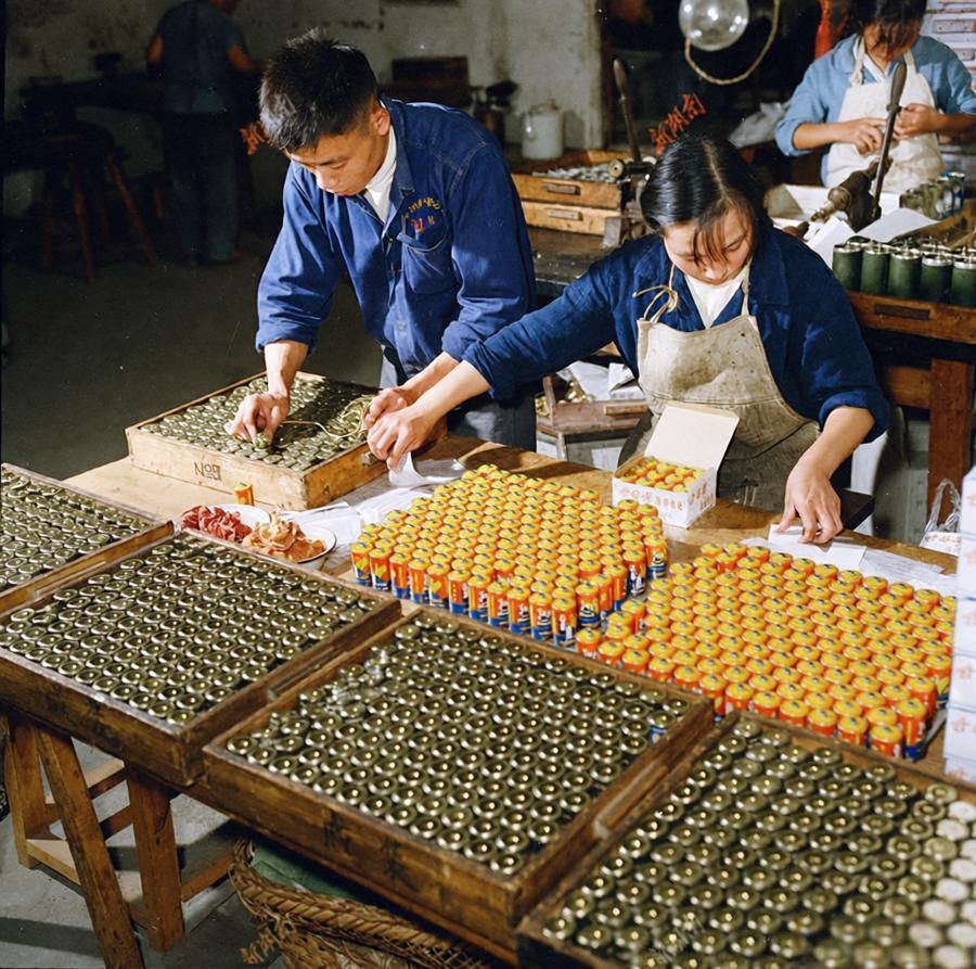 这是1965年9月株洲电池厂的生产现场照片，两位工人正专注地在工作台前忙碌，男工