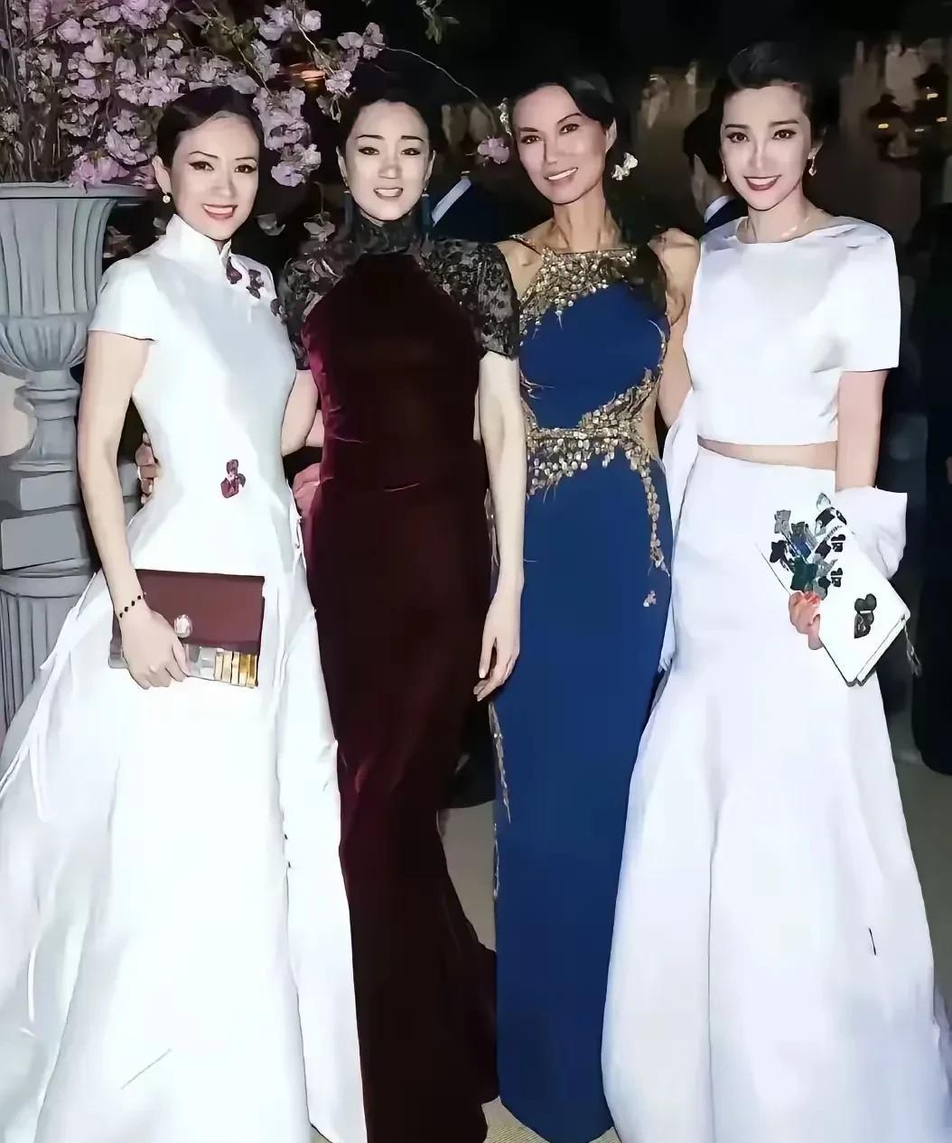 这是4位女明星的合影照，章子怡和李冰冰都身着白色衣服，手上拿着包包。巩俐一身酒红