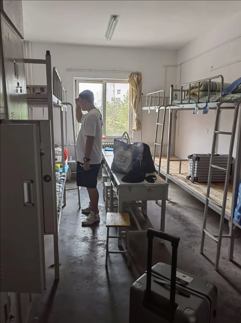 2023年，一张家长送孩子入读青岛大学的宿舍照片被记录了下来。八人间，上下铺，水