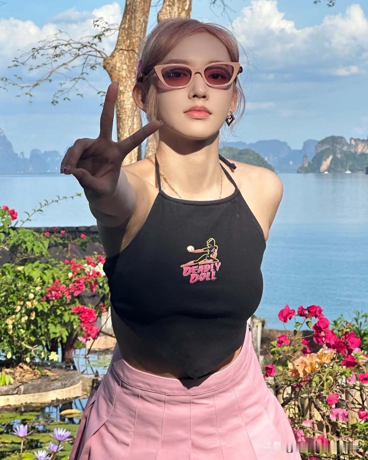 粉发配粉裙，黑色挂脖肚兜式短上衣，往泰国那片水天之间一站——花丛围着、水面衬着，