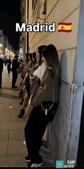 文明发达国家的夜景。一排漂亮的姑娘排队看手机。