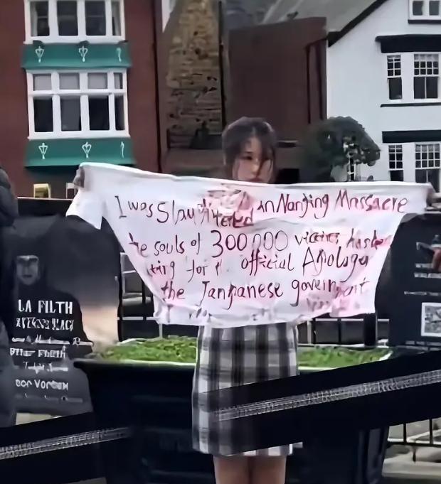 2022年，中国女留学生在英国街头，脸画着“伤疤”身穿旗袍，高举横幅，上面写着：