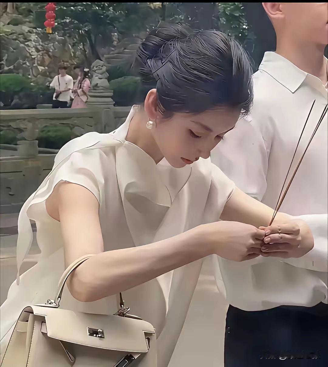 在寺庙偶遇一位漂亮姑娘虔诚求姻缘，着实惹人好奇。她身着淡色长裤、雪白上衣，眉清目
